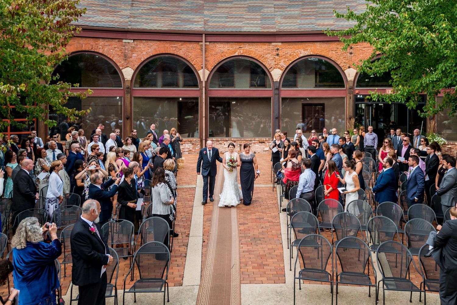 Outdoor wedding ceremony setup with rows of chairs facing brick archways.