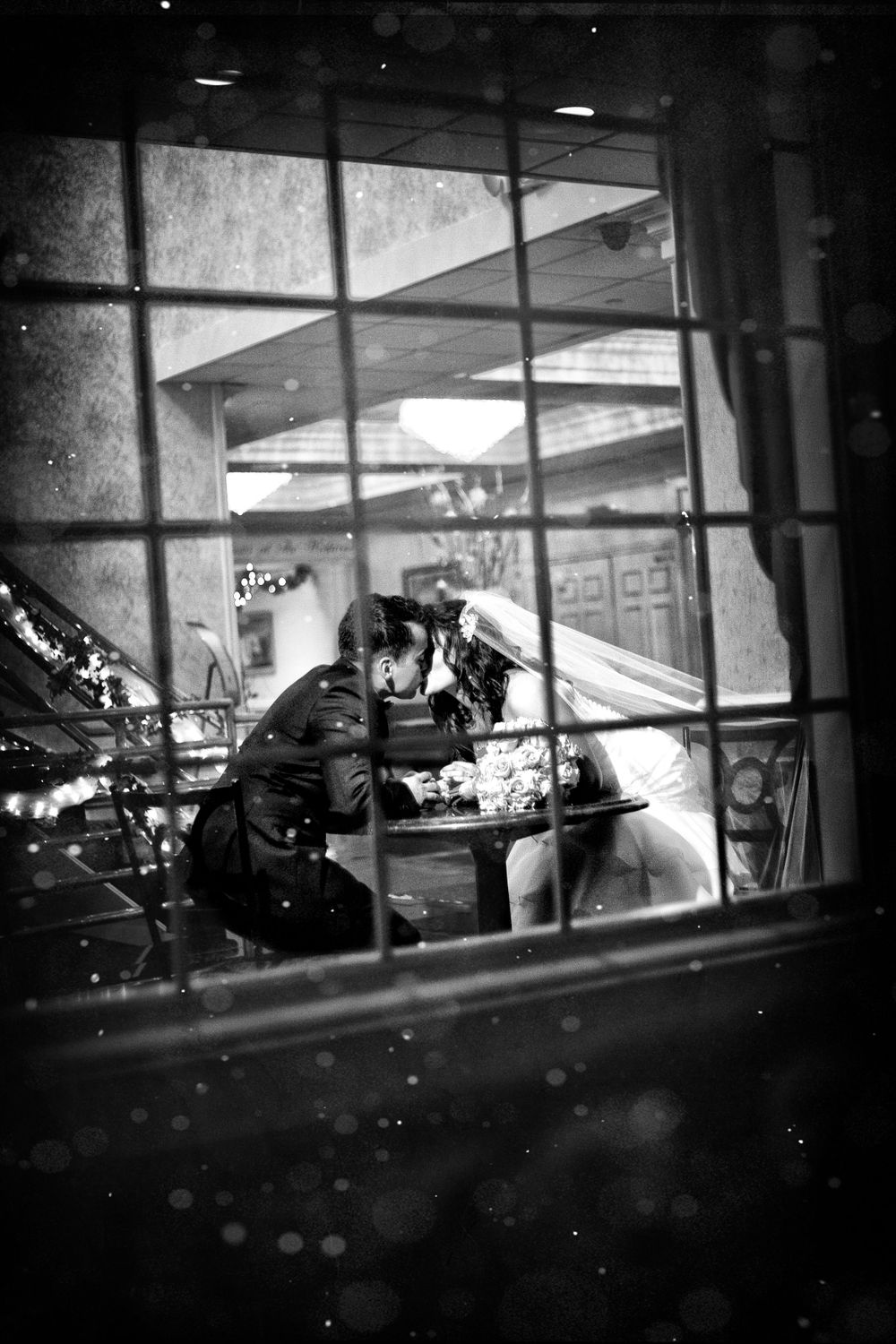 a black and white image of the bride and groom kissing, in the style of christophe jacrot, lively tavern scenes