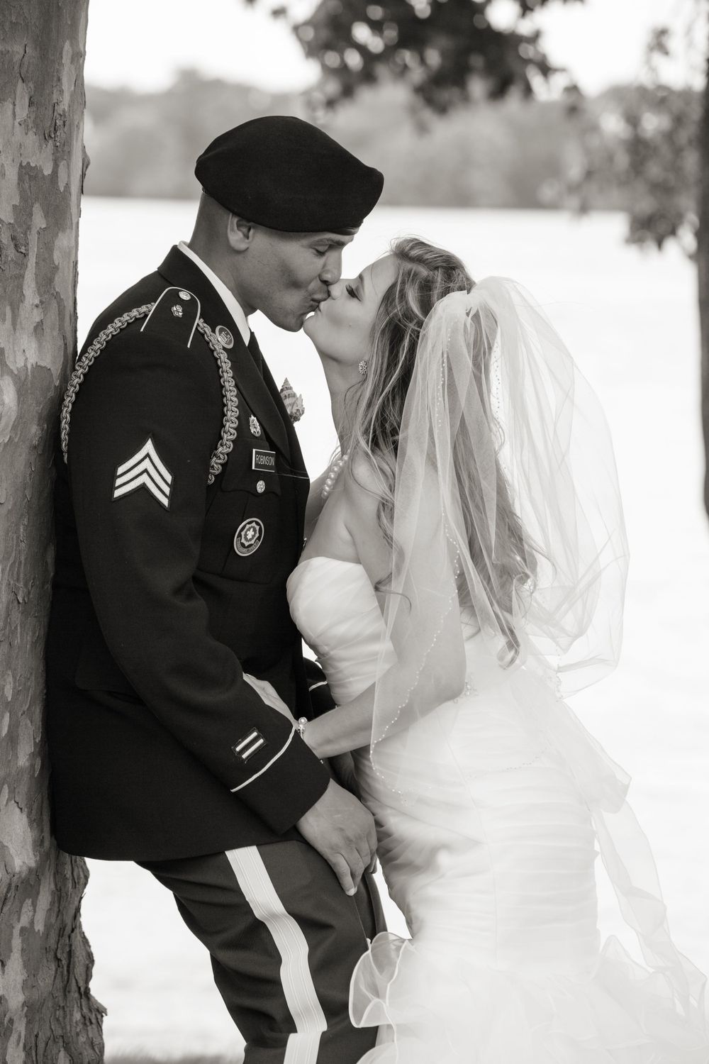 bride and groom kissing beside a tree, in the style of meticulous military scenes, boldly black and white, snow scenes