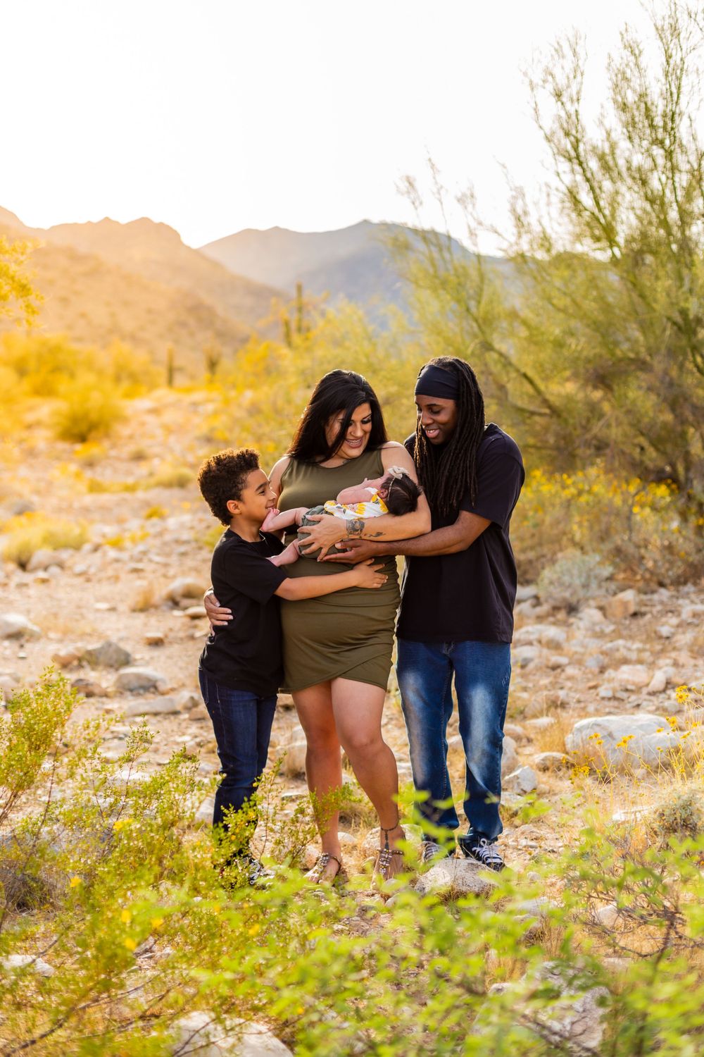 Family maternity photo in desert landscape during golden hour.