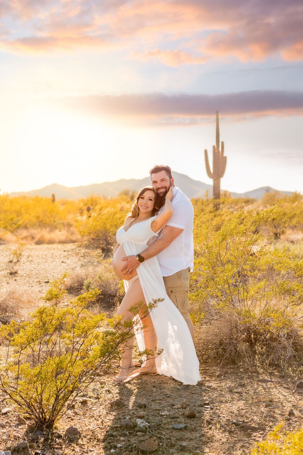 Romantic desert engagement photo with saguaro cactus during golden hour sunset.