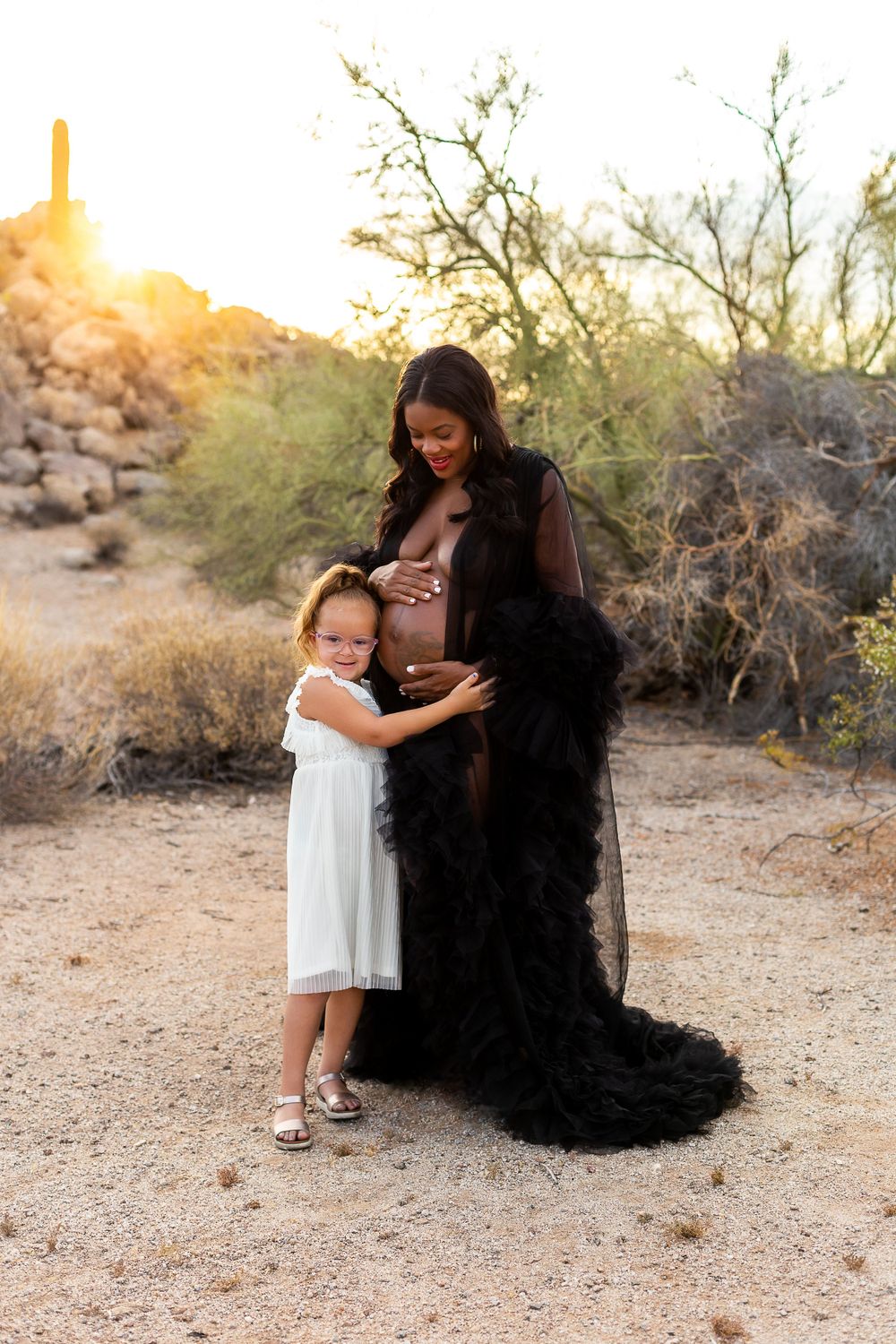 Maternity photo shoot in desert landscape at sunset with flowing black gown.