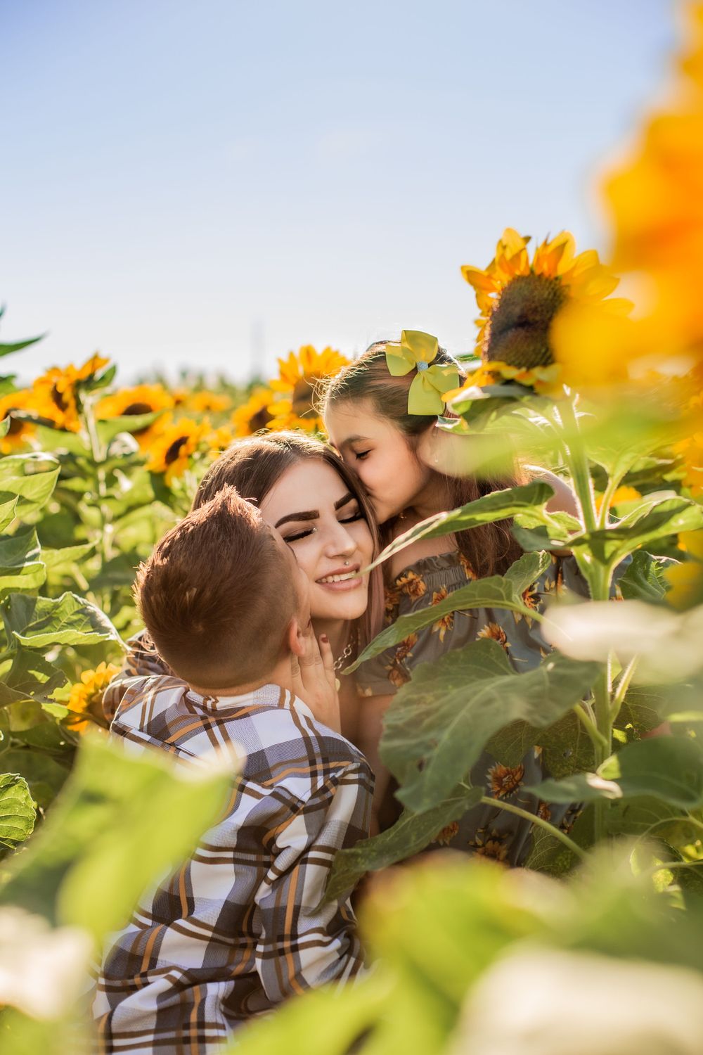 Couple sharing an intimate moment in a vibrant sunflower field during golden hour.
