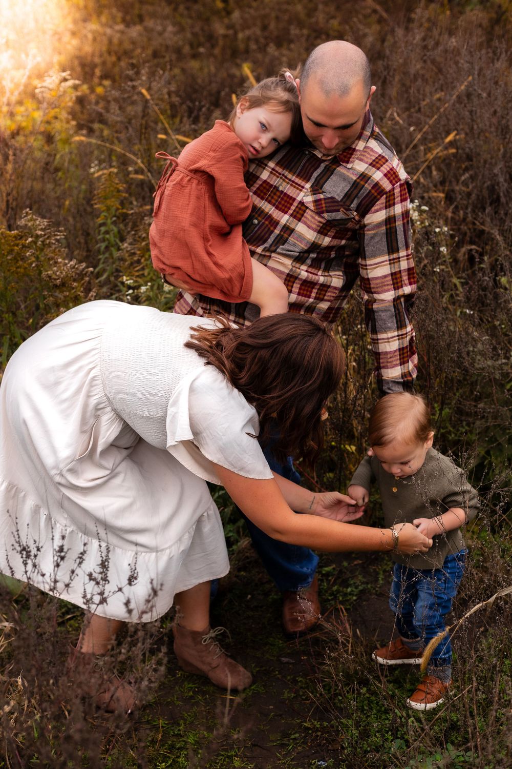 Family sharing an intimate moment outdoors during golden hour in a field.