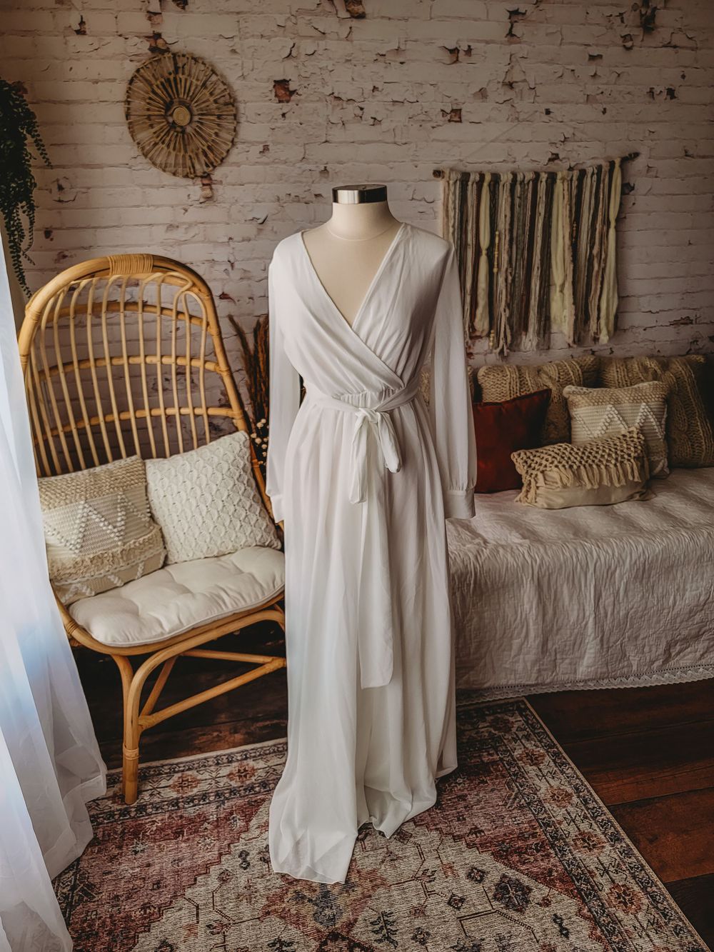 Ivory long sleeve wrap maxi dress with self-tie waist on a mannequin in a bohemian decorated room.