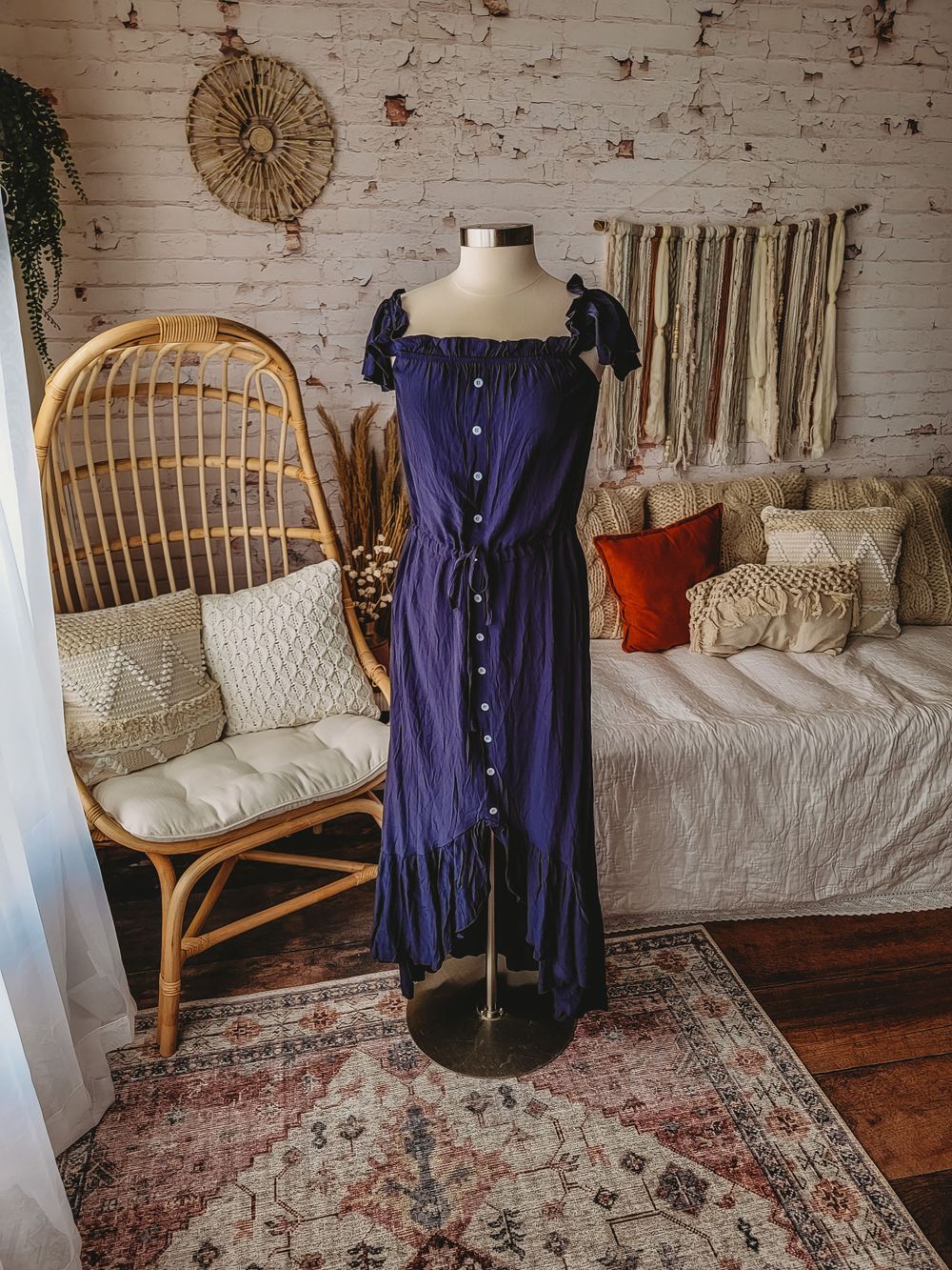 Navy blue button-front cap sleeve midi dress with ruffle hem on mannequin in boho room.