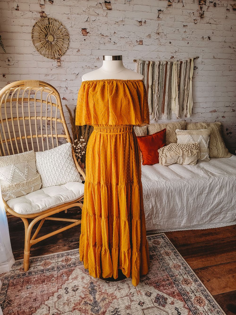 Mustard yellow off-shoulder tiered maxi dress with lace detail on mannequin in boho room.