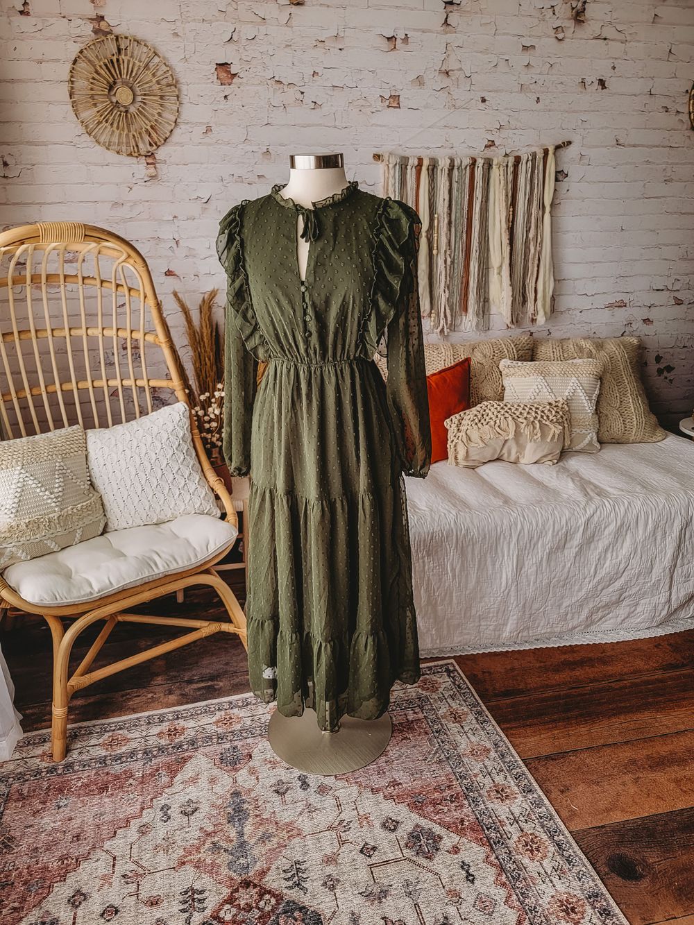 Olive green ruffle sleeve tiered maxi dress with tie neck on mannequin in boho room.