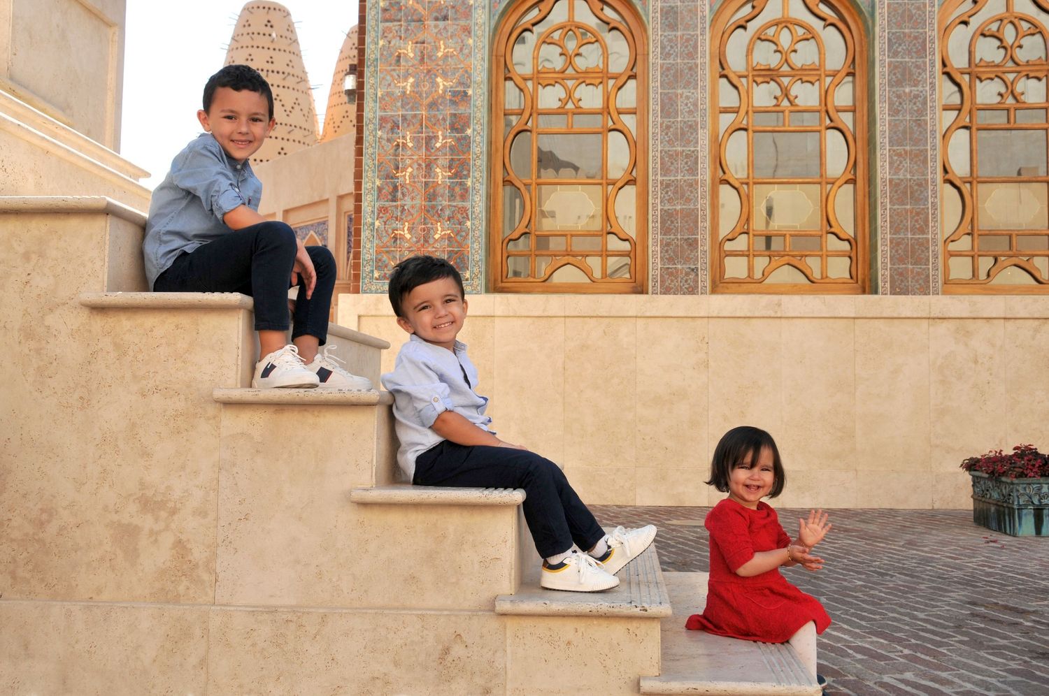 Photo of three sibling children near structures in Doha, Qatar