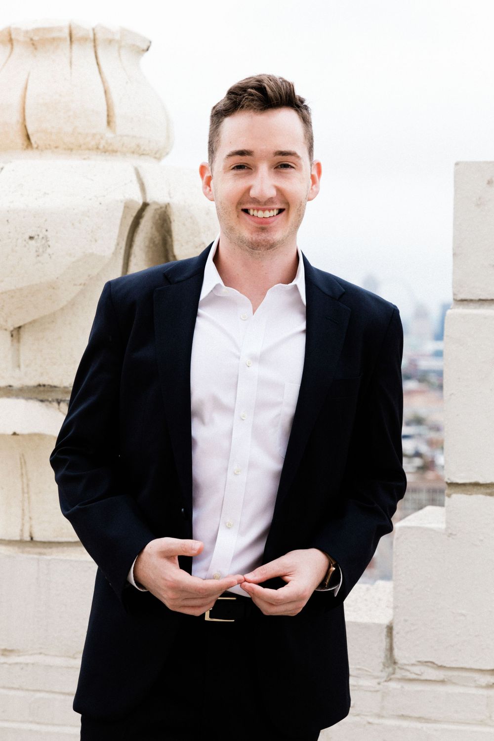 Professional portrait of person in suit against architectural backdrop.