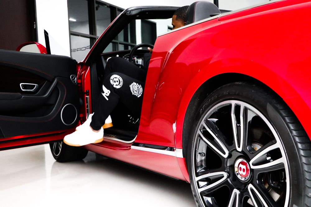 Close-up shot of a red luxury car's wheel and open door in a showroom.