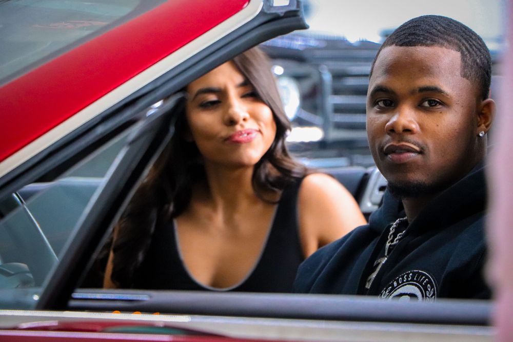 Models seated inside a luxury vehicle pose for a casual photoshoot.