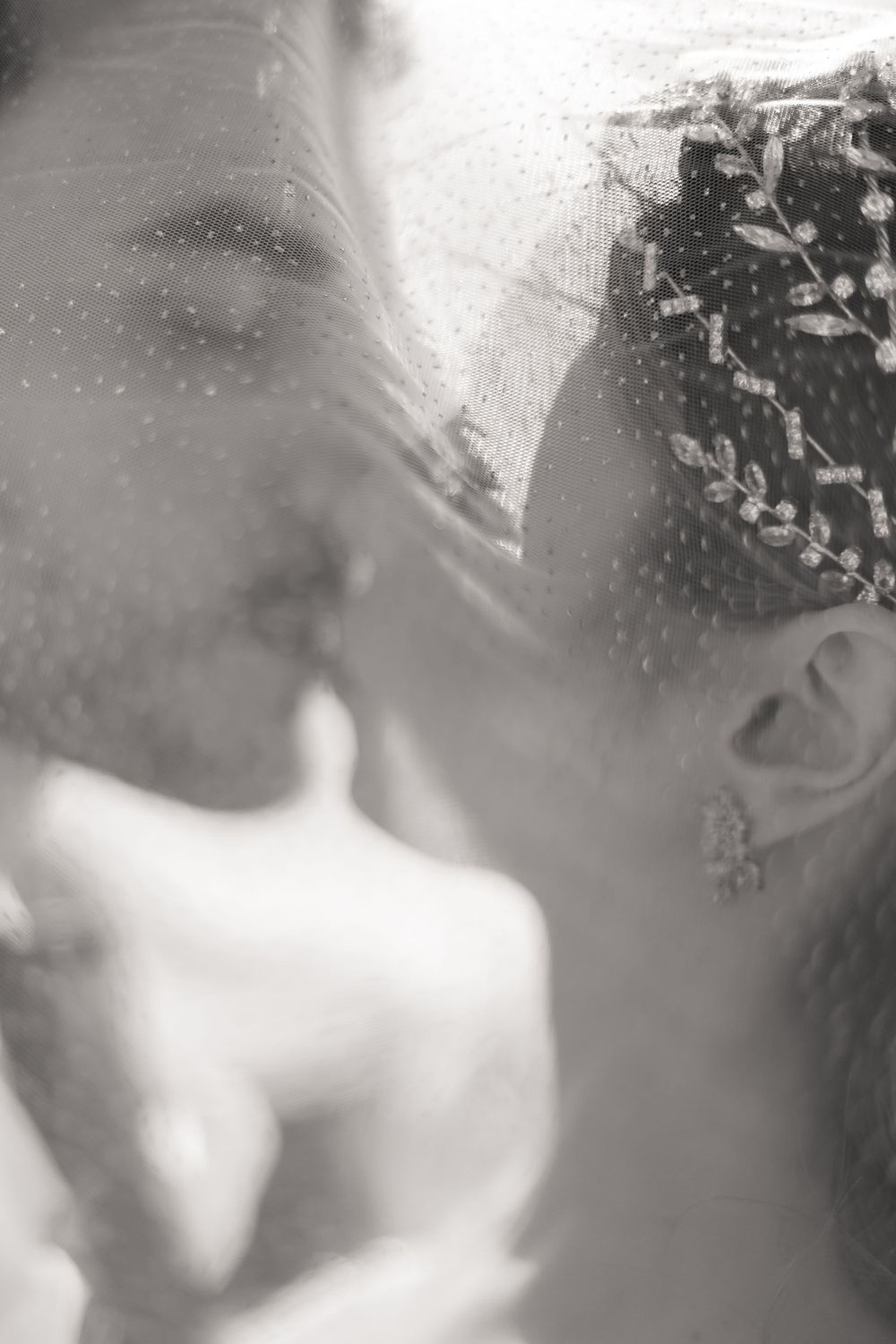 Soft black and white close-up photo showing romantic wedding details with delicate lighting.