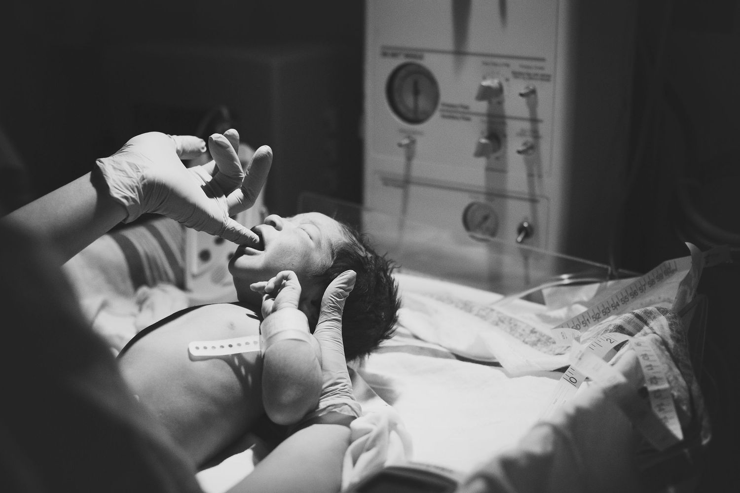 Newborn baby boy being checked out after birth by hospital nurse.