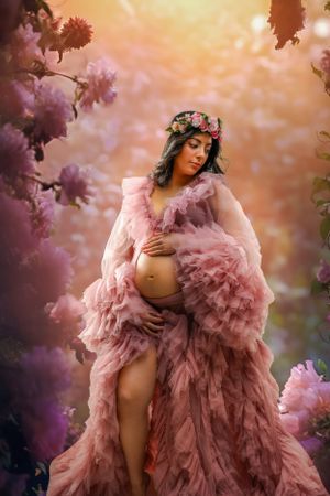 Ethereal maternity photos in pink tulle gown surrounded by cherry blossoms.