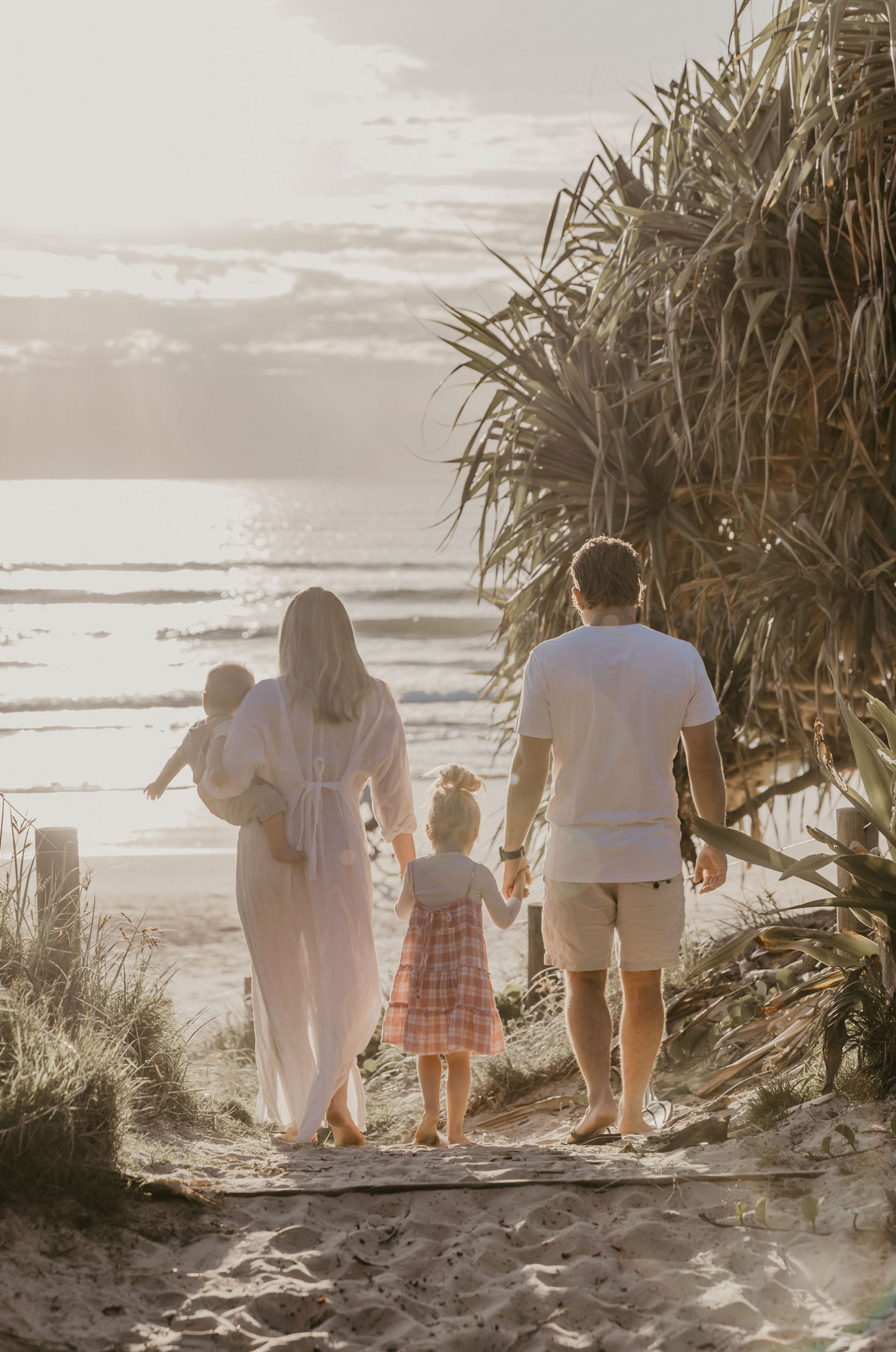 Family walking together towards the beach at sunset during a relaxed Byron Bay wedding celebration.