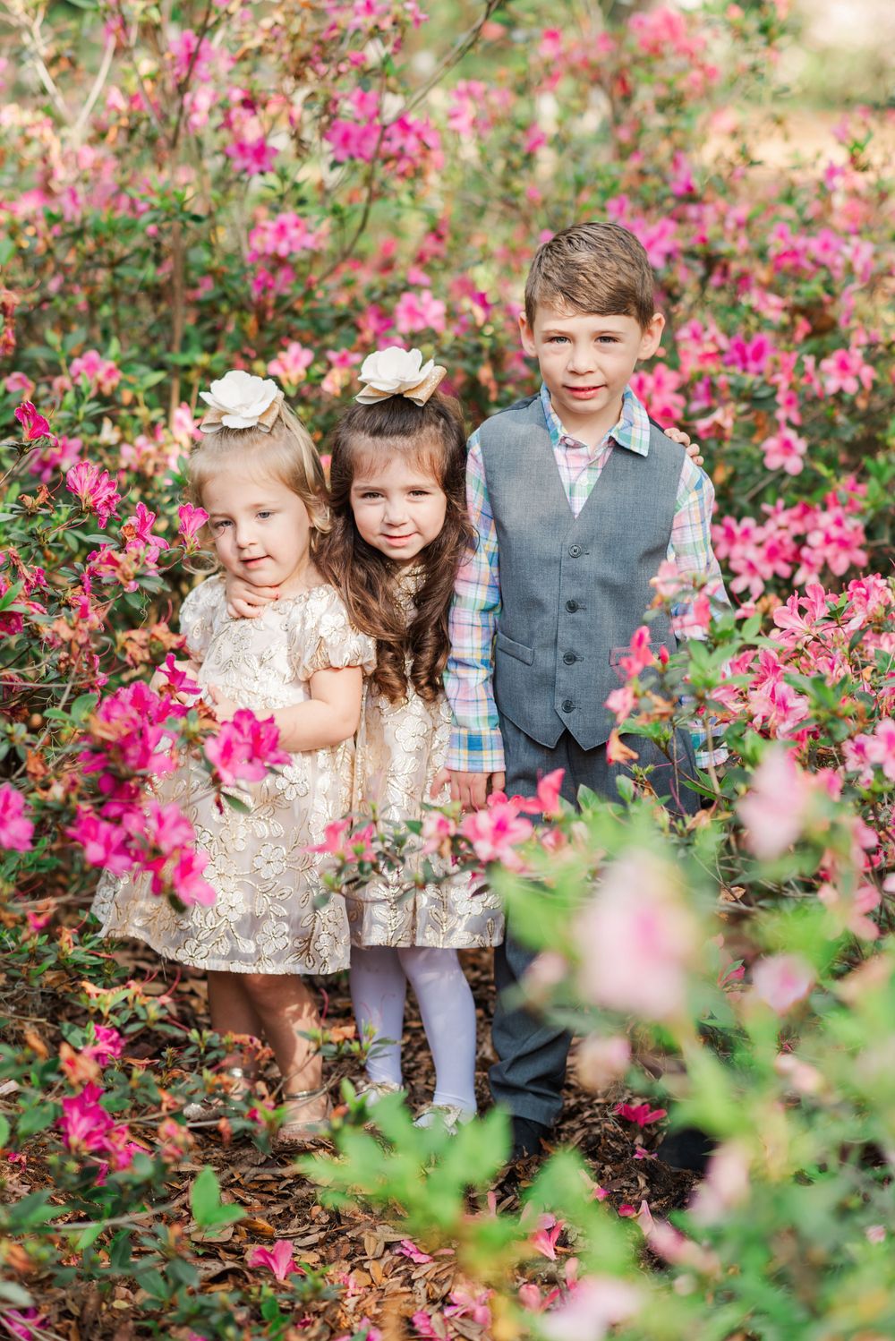 three children pose in the azalea bushes at Bok Tower Gardens in Lake Wales, Florida