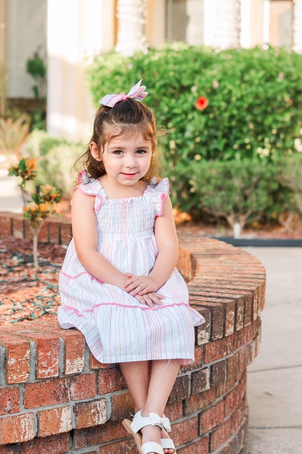 four year old toddler sits on brick wall in downtown Winter Haven, Florida