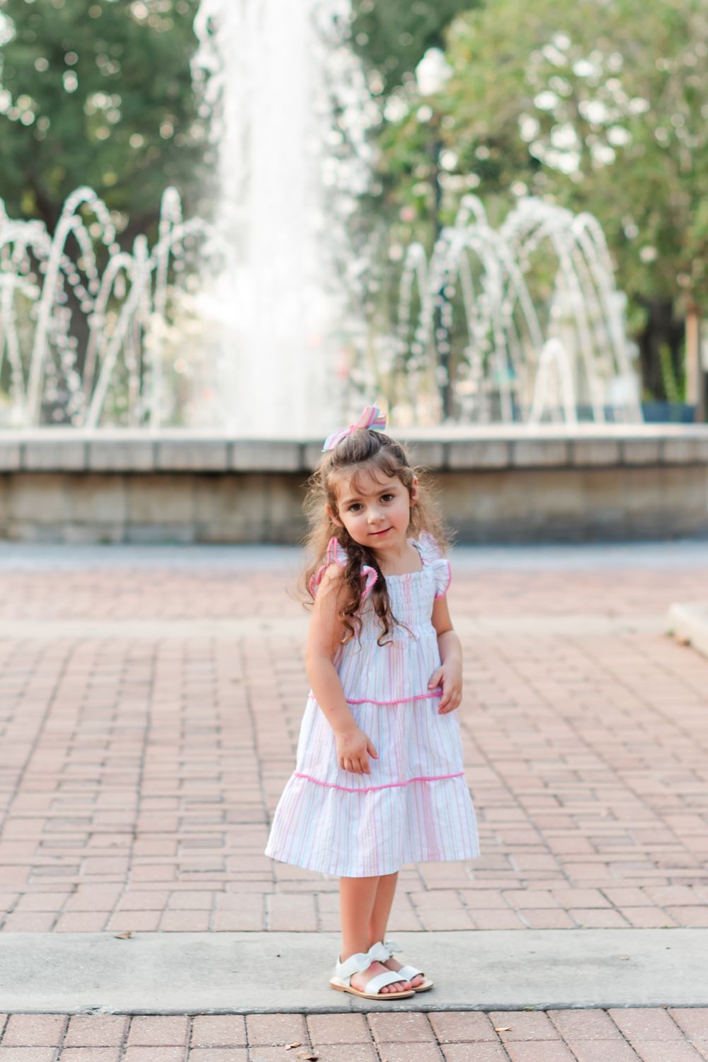 little girl stands in front of fountain in Central Park in Winter Haven, Florida