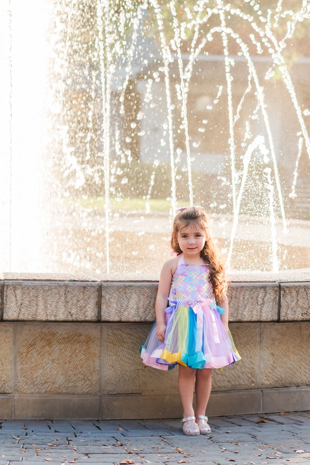 little girl stands in front of fountain in Central Park in Winter Haven, Florida
