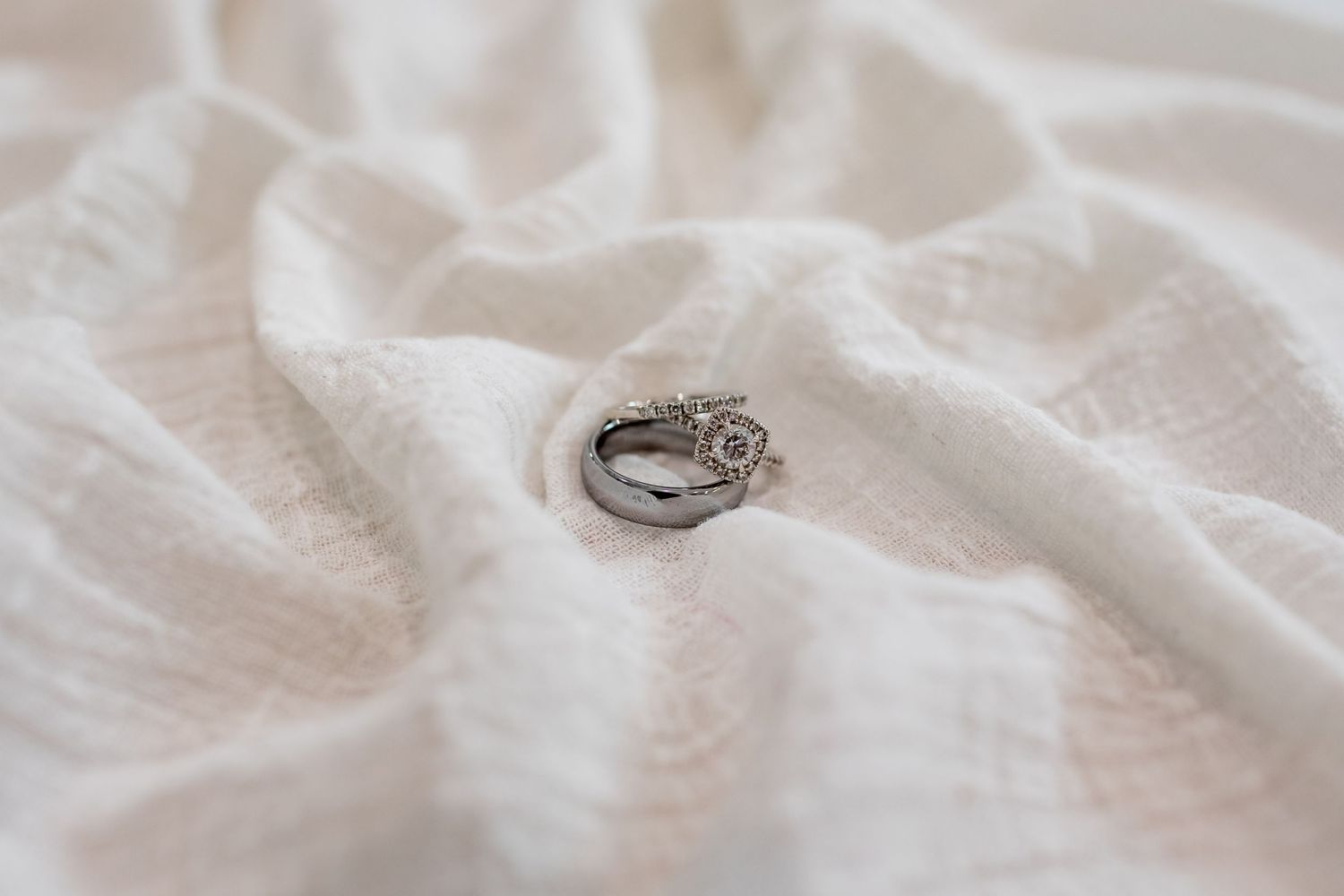 Wedding rings placed on white textured fabric in natural light.