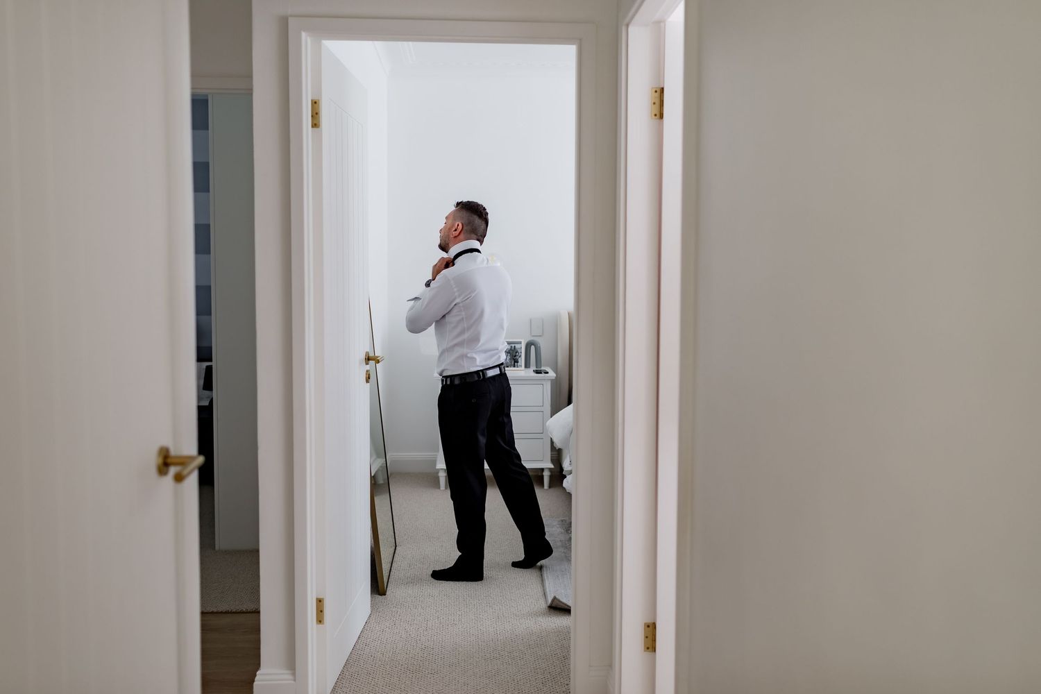 Wedding preparations reflected in hallway mirror with formal attire.
