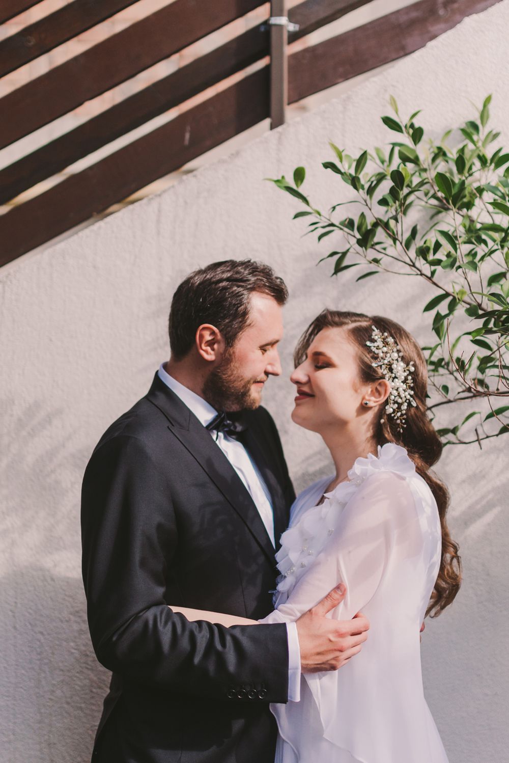 A romantic wedding couple shares tender moments in a series of intimate portraits against a white wall.