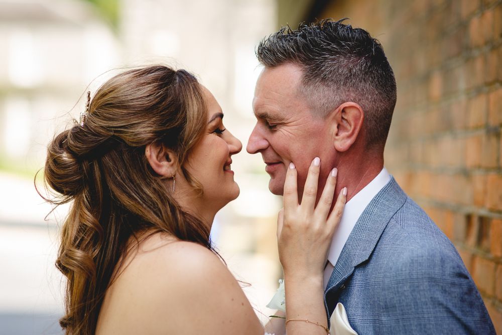 Intimate romantic moment between couple against rustic brick wall.