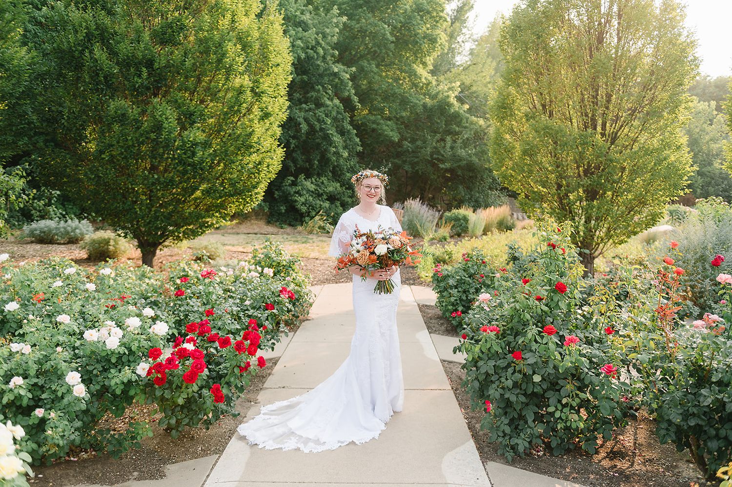 A beautiful garden wedding scene with red and white roses lining a concrete pathway.