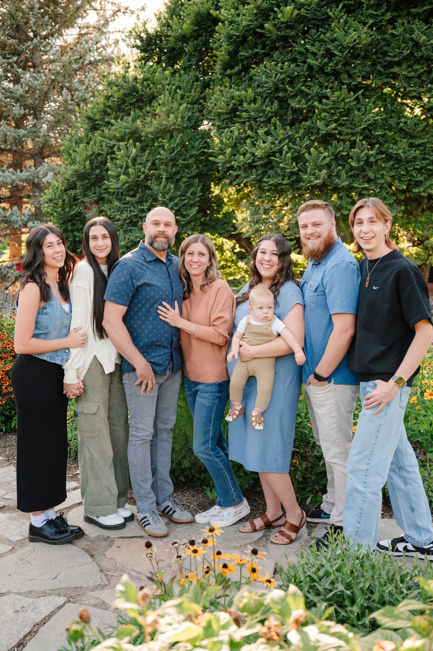 A group of people standing together in a garden setting with flowers and greenery.