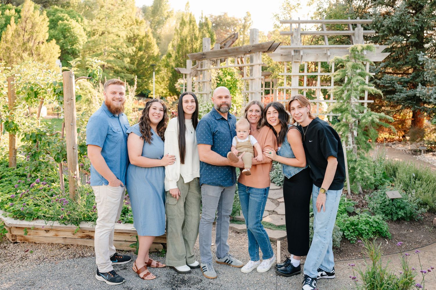 A group portrait of people standing together in a garden with a white trellis structure.