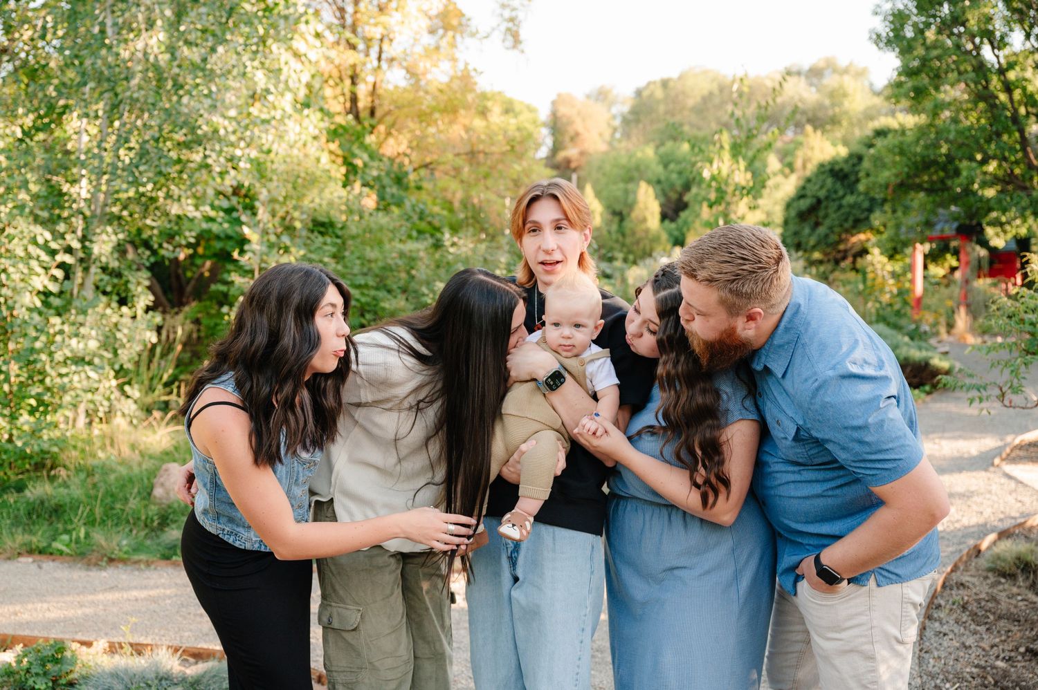 A group of friends share a laugh together while gathered on an outdoor garden path.