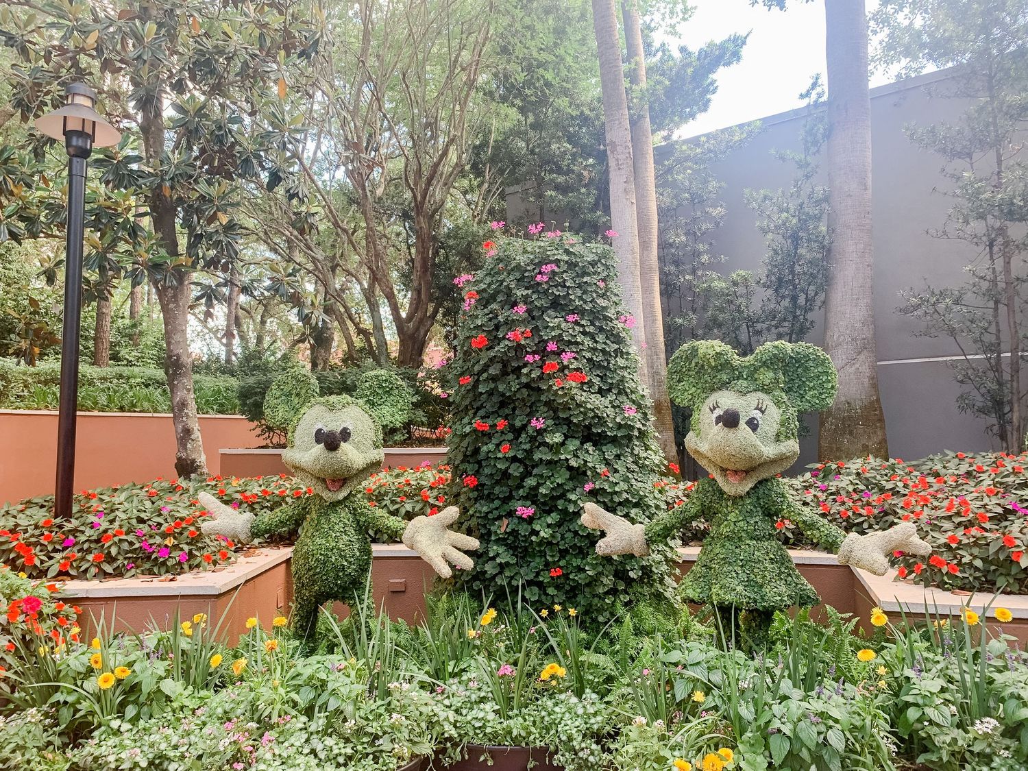 Garden landscape featuring ornamental owl sculptures among colorful flower beds and greenery.