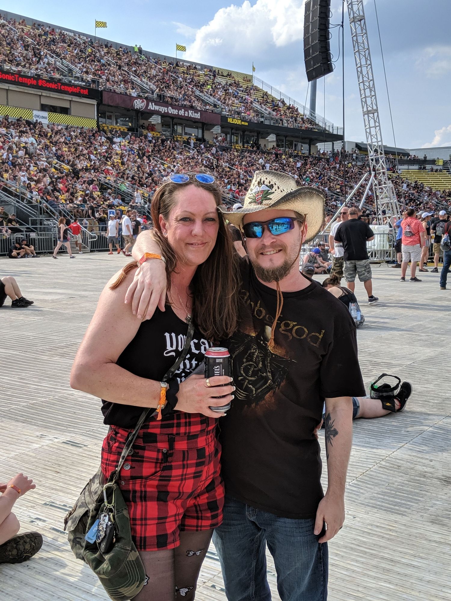 A husband and wife at a concert. The husband is wearing a cowboy hat and sunglasses