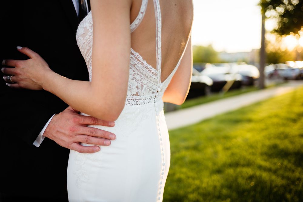 Closeup of couple embracing showing detailed lace back of white wedding dress.