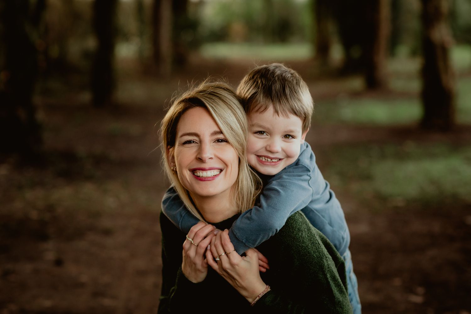 A joyful outdoor portrait showing genuine laughter and embrace in a forest setting.