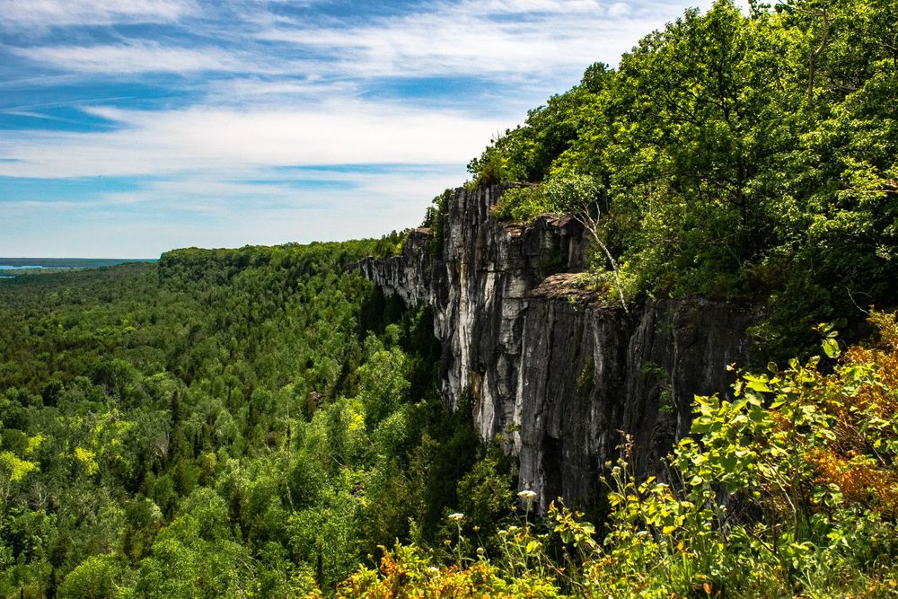 Panoramic view of forested cliffs and green valleys under blue summer skies.