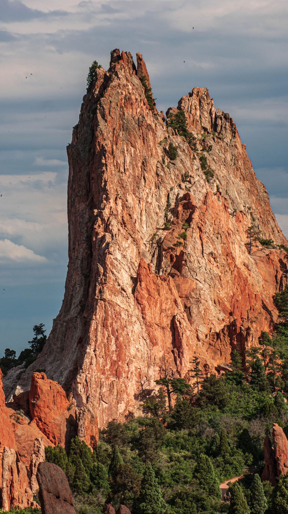Towering red sandstone formations rise dramatically against a cloudy sky at Garden of the Gods.
