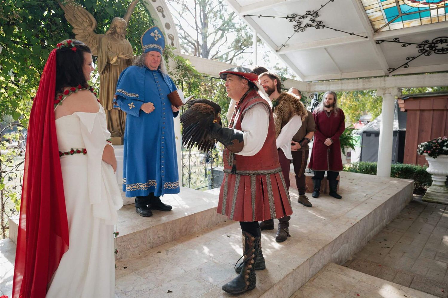 Wedding party in medieval attire performs on raised platform during ceremony.