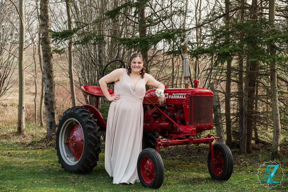 Formal portrait with vintage red Farmall tractor among evergreen trees.