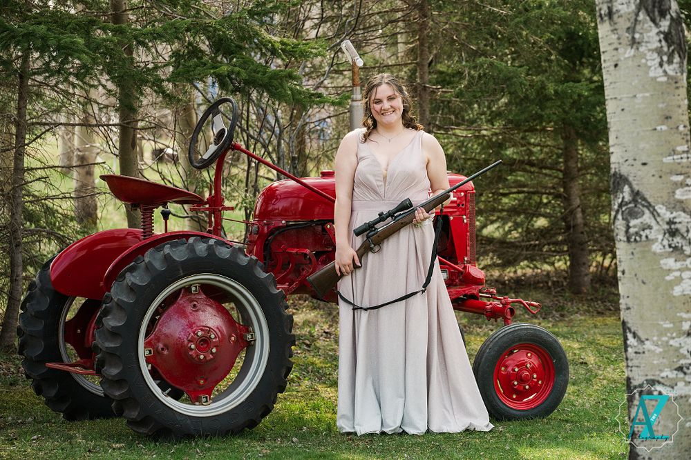 Elegant white dress photographed with a vintage red farm tractor in a forest setting.