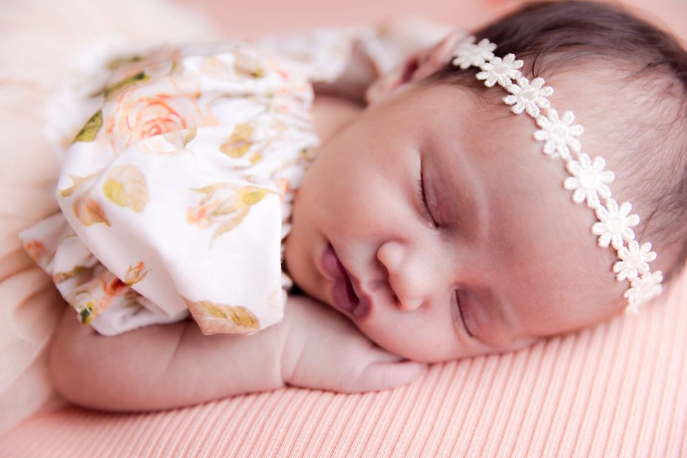 sleeping baby with flower headband in a flowery dress
