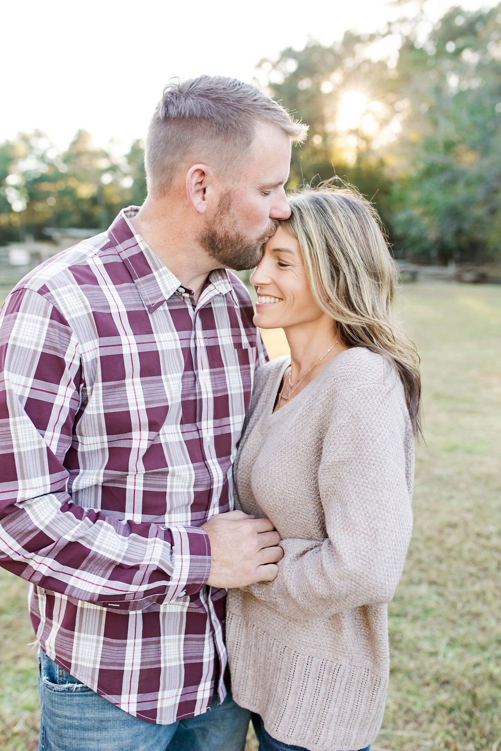 Romantic outdoor portrait of a couple in casual fall attire sharing an intimate moment at sunset.