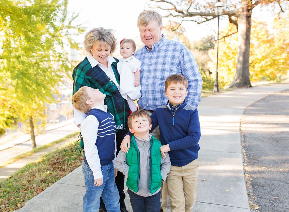 Multi-generational family group poses together outdoors on autumn day.