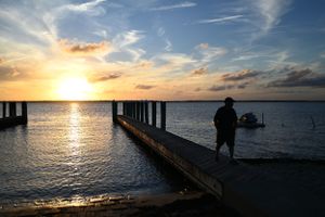 Panoramic view of a scenic pier at sunset with golden light reflecting off calm ocean waters.