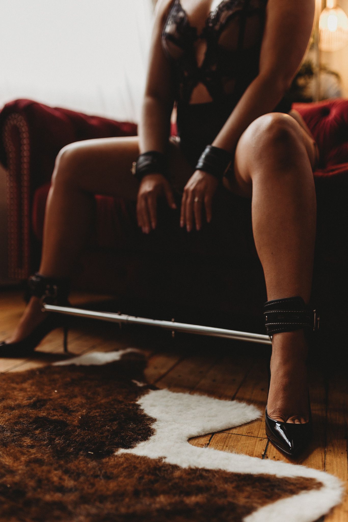 Artistic photo of restraints and heels on hardwood floor with fur rug.