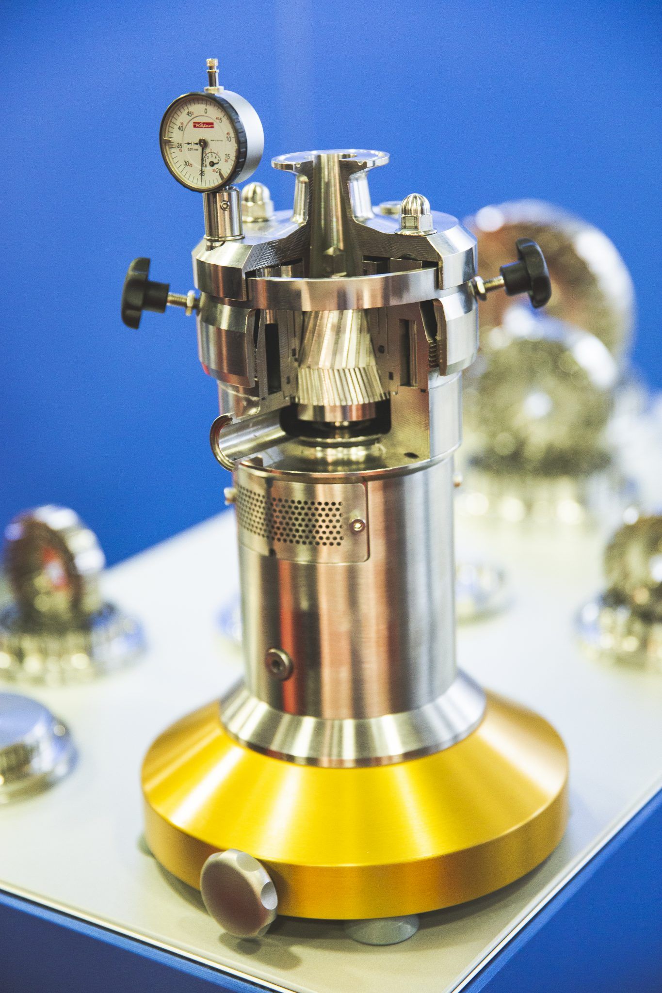 Scientific pressure gauge instrument with metallic finish against blue background.
