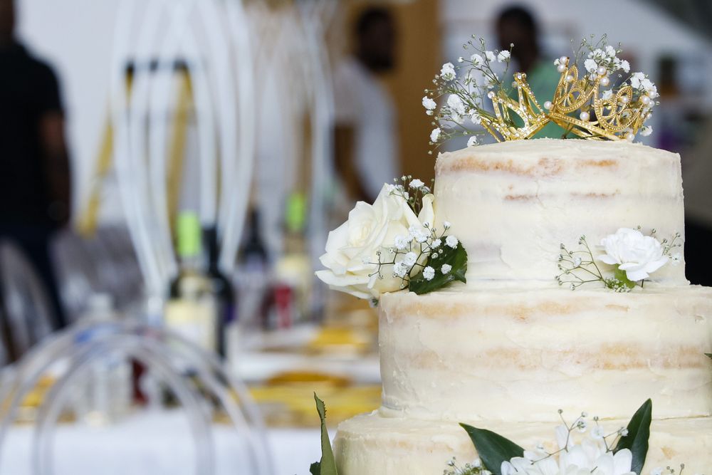 White wedding cake decorated with delicate flowers and greenery on a formal table setting.