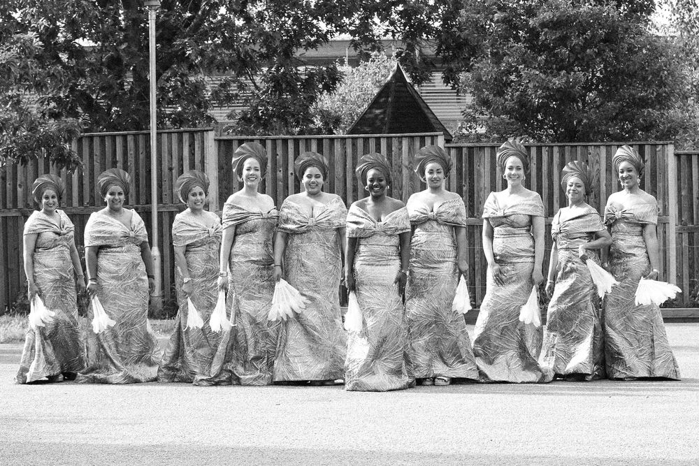 Wedding party members lined up outdoors for a panoramic group photograph.