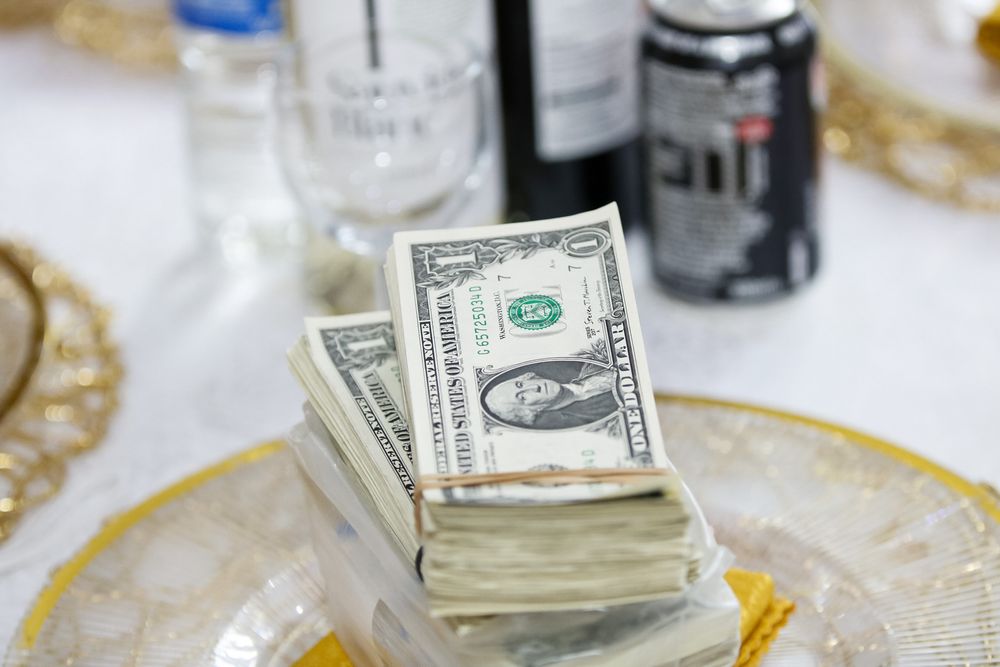 Stack of dollar bills displayed on decorative gold-rimmed plates at reception.